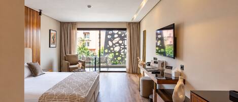 A hotel room with a bed, desk, chair, and a view through the window.