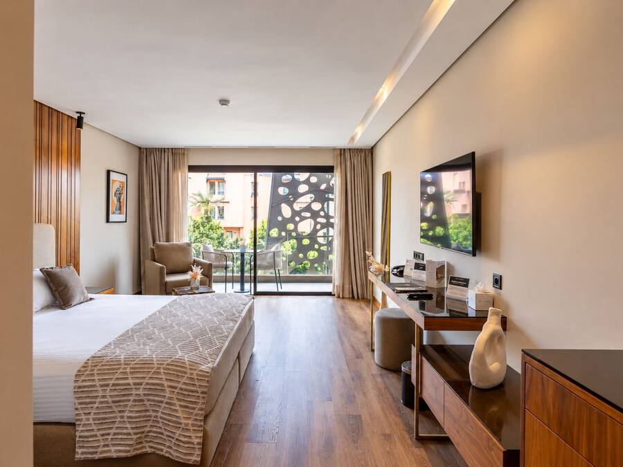 Habitación de hotel con cama, escritorio, silla y vistas a través de la ventana.