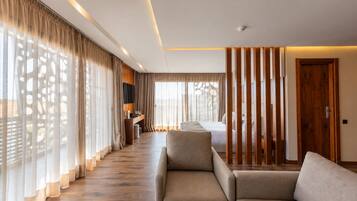 Habitación de hotel con cama, escritorio, sofá y vistas al exterior.