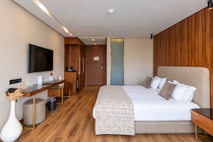 Una camera d'albergo moderna con un letto grande, una scrivania, una TV a schermo piatto e un pannello decorativo in legno.