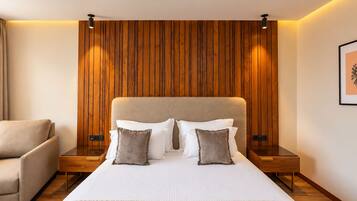Un dormitorio moderno con una cama grande, dos mesitas de noche, una silla y un panel de pared de madera.