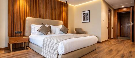 Un dormitorio moderno con una cama grande, paneles de madera en la pared, una mesita de noche y una puerta.