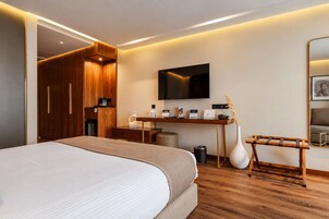 Una moderna camera d'albergo con un ampio letto, una scrivania con TV a schermo piatto, pannelli in legno e uno specchio.