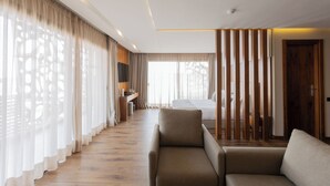 Une chambre d’hôtel avec un canapé, un lit, un bureau et une grande fenêtre avec des rideaux.