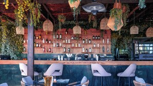A bar area with wicker chairs, a wooden counter with bottles, and hanging planters. - Longue Vie Hôtels (Marrakech)