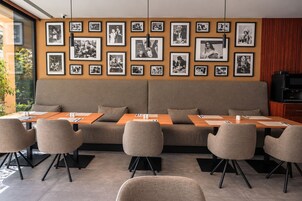 Un'area lounge moderna con divano e poltrone, fotografie incorniciate appese al muro e un televisore.
