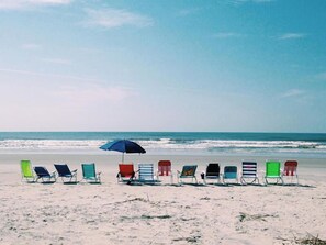 Une plage bordée de rangées de chaises longues et abritée par un seul parasol.