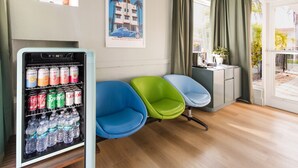 A room with a vending machine, two chairs, a poster, and a view of the outdoors.