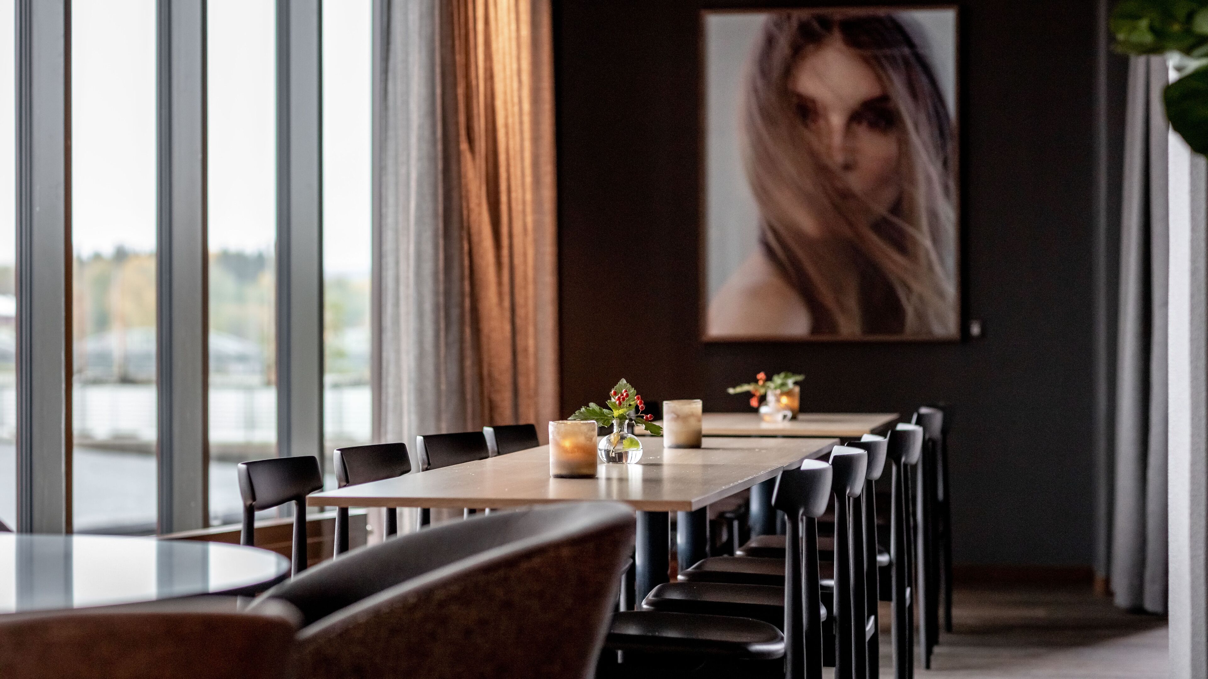 A modern dining area with a long table, multiple chairs, and a vase with flowers.