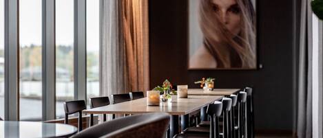 A modern dining area with a long table, multiple chairs, and a vase with flowers.
