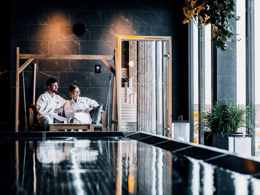 A spa area with a wooden bench, a stone wall, and a large window.