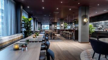 Un restaurant moderne avec de longues tables, des banquettes et un espace bar.