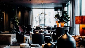 A modern hotel lobby with a large window, seating area, and a decorative plant. - Clarion Hotel Umea (Umea)