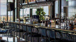 A bar area with a long counter, black chairs, and a variety of bottles and glasses. - Clarion Hotel Umea (Umea)