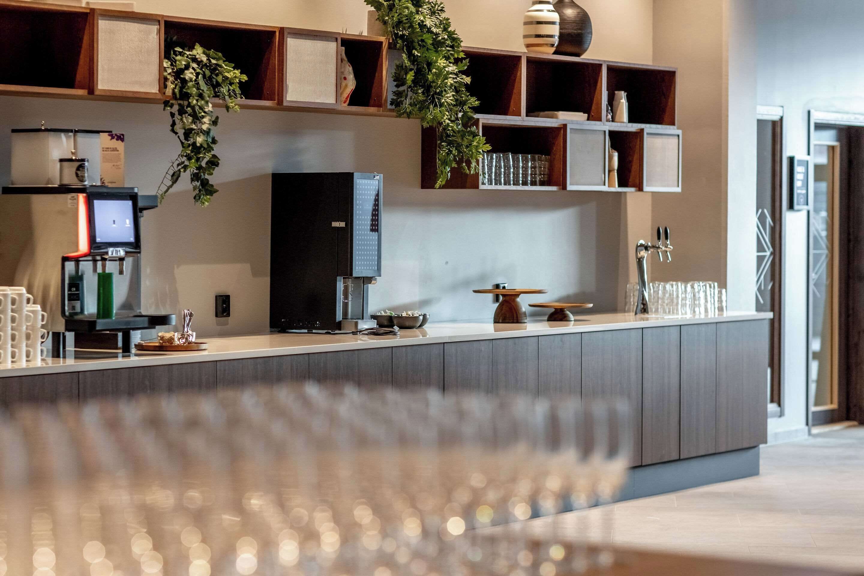 Una cocina moderna con cafetera integrada, un refrigerador grande y una encimera de madera.