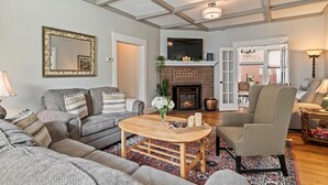 A living room with a fireplace, sofas, a coffee table, and a large mirror.