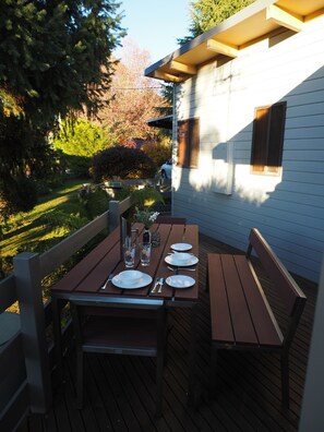 Een buitenterras met een houten tafel voor vier personen, omringd door houten stoelen.