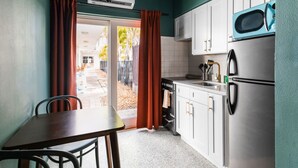 A compact kitchen with white cabinets, a stainless steel refrigerator, and a blue microwave. - 108 · ☀Pool✔ Kitchen✔ Beach✔ Self Checkin✔ Free Parking✔ (Clearwater)