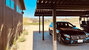 A modern house with a covered garage, a parked car, and a vineyard in the background. - Dwell Magazine Featured Vineyard Home (Paso Robles)