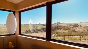A room with large windows offering a view of vineyards and rolling hills. - Dwell Magazine Featured Vineyard Home (Paso Robles)