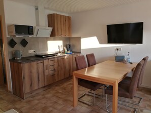 Eine moderne Küche mit Holzschränken, einer eingebauten Mikrowelle und einem Essbereich mit Tisch und Stühlen.