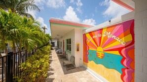 A corridor with a colorful mural, palm trees, and a bench.