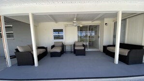 A covered patio area with wicker furniture and a sliding glass door leading to an outdoor space. - Villa in Rotonda West with huge screened lanai and canal view (Rotonda West)