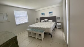 A bedroom with a bed, bedside tables, a bench with 'Welcome' written on it, and two wall-mounted lamps. - Villa in Rotonda West with huge screened lanai and canal view (Rotonda West)