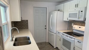 A compact kitchen with a stainless steel sink, white cabinetry, a microwave, and a built-in oven. - Villa in Rotonda West with huge screened lanai and canal view (Rotonda West)