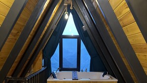A cozy attic bedroom with a skylight, a large bed, and a built-in bathtub. - Puleri Dağ Evi (Camlihemsin)