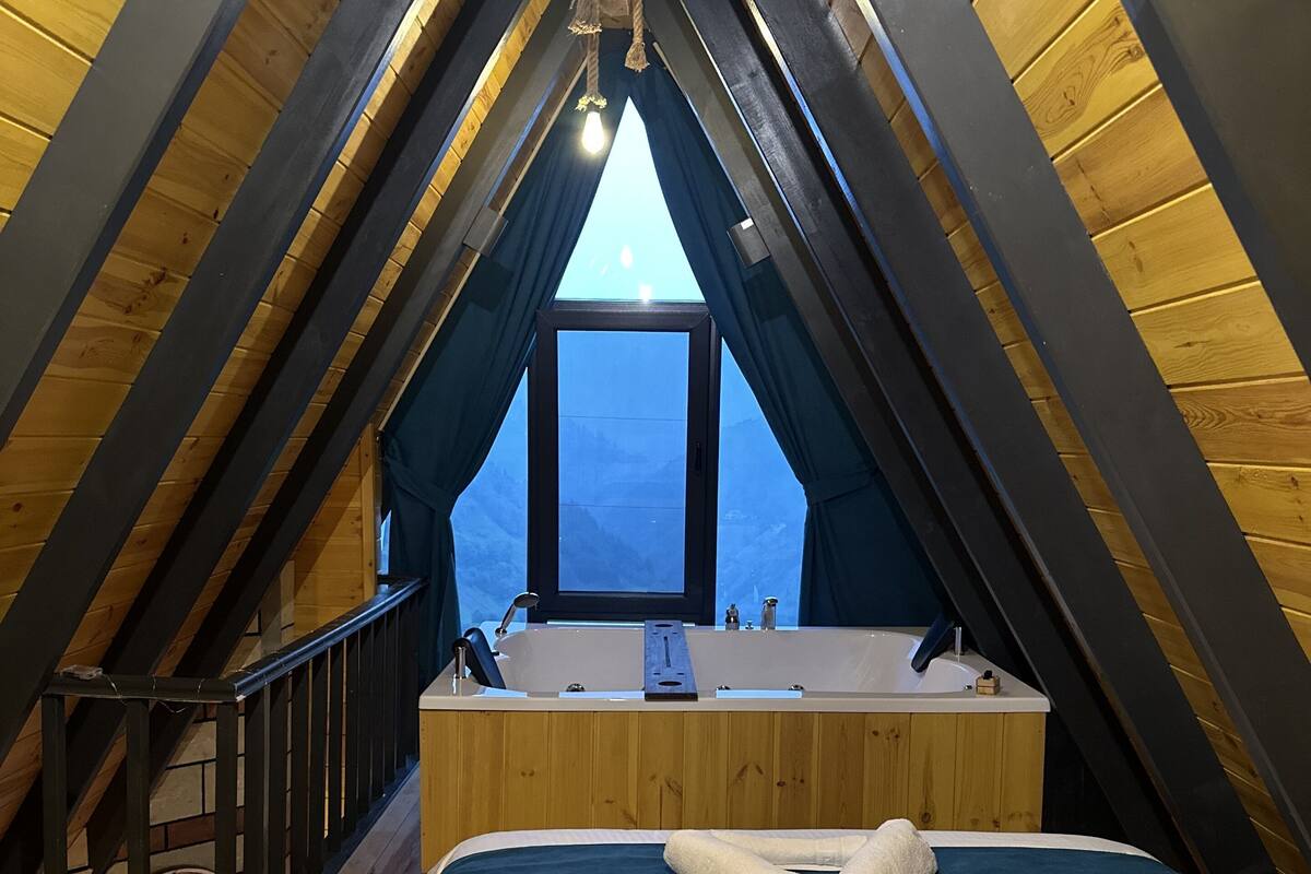 A cozy attic bedroom with a skylight, a large bed, and a built-in bathtub.