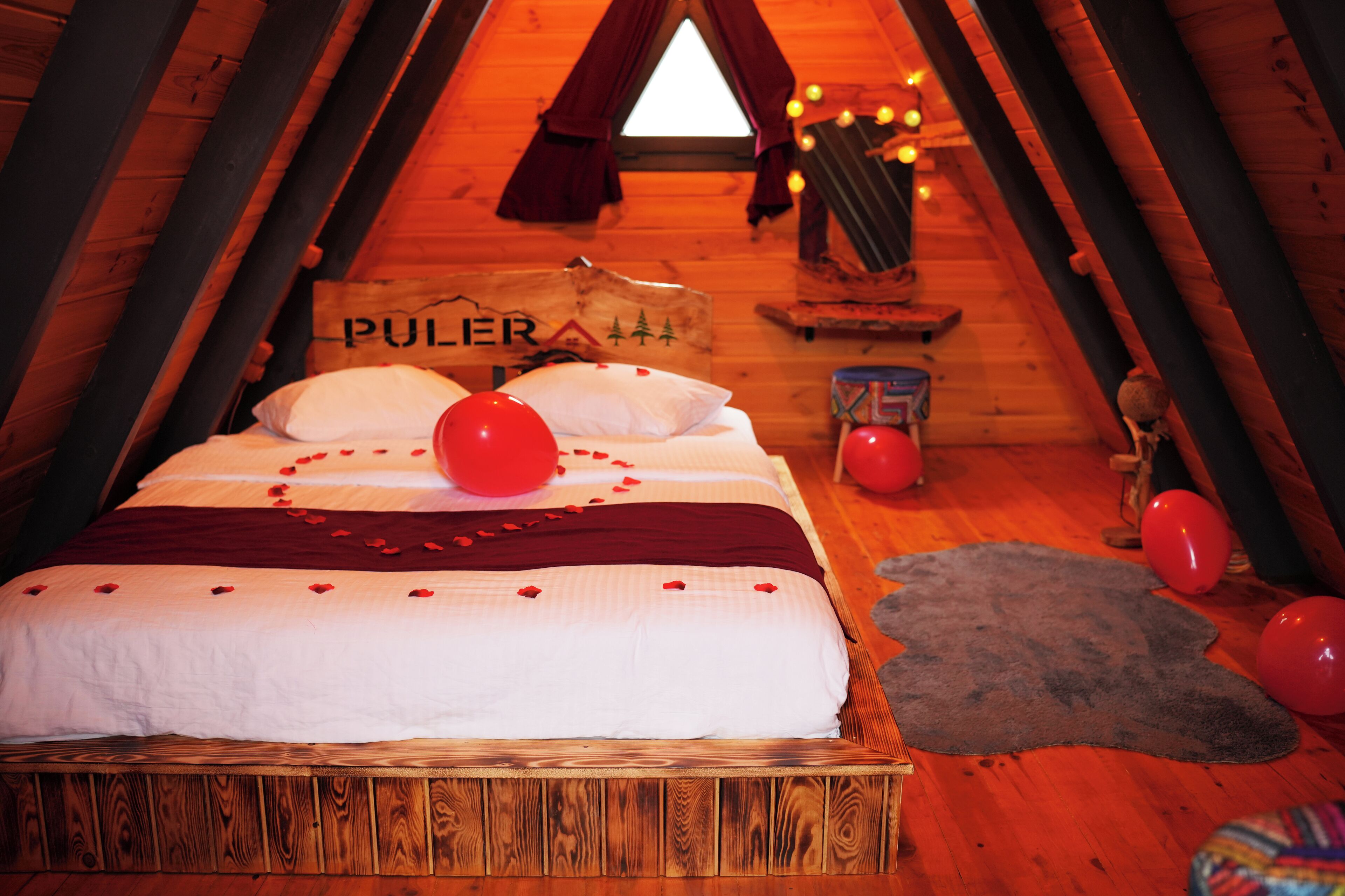 A cozy wooden cabin bedroom with a bed, pillows, and a sign that reads "PULER".