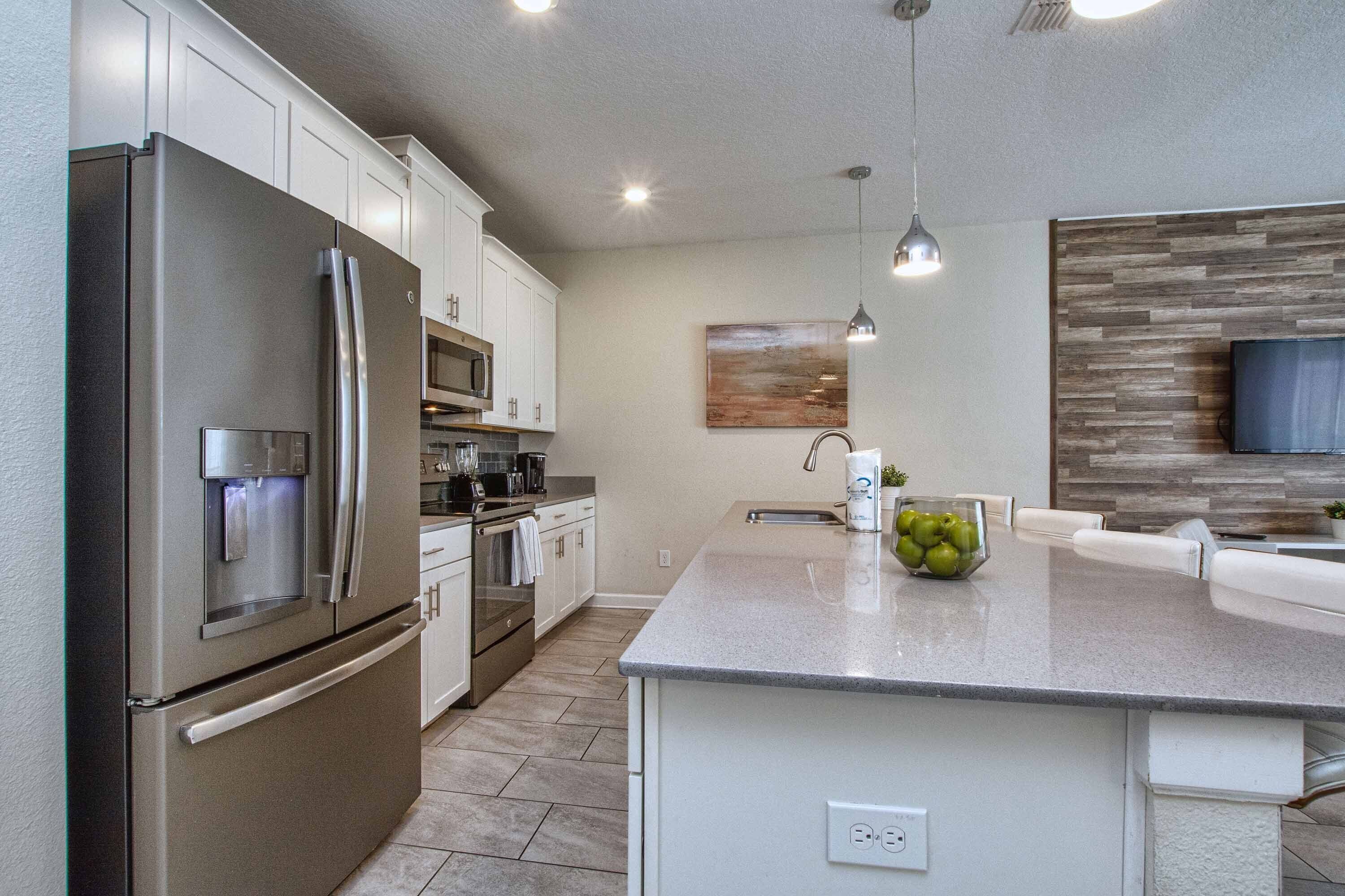 A modern kitchen with stainless steel appliances, a central island, and a wooden accent wall.