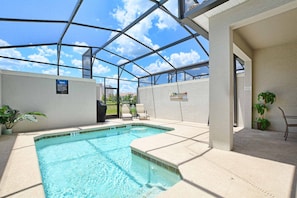 Une piscine intérieure dotée d’un toit en verre, entourée de murs et agrémentée de quelques plantes en pot.