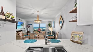 Une cuisine moderne dotée d’un grand îlot central, d’un évier en acier inoxydable et d’un lustre.