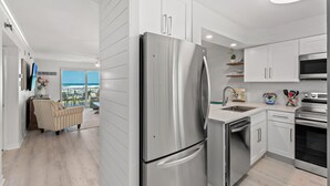 Une cuisine moderne dotée d’appareils électroménagers en acier inoxydable, de meubles blancs et offrant une vue sur l’extérieur.