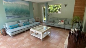 Una sala de estar con un cuadro grande de una ola, dos sofás, una mesa de centro y un aparador de madera.