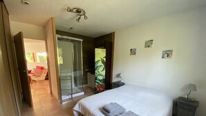 Un dormitorio con cama, mesita de noche, puerta a un balcón y vistas al exterior.