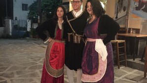 Drie personen in traditionele kledij op een versierd voetpad.