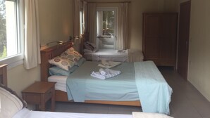 Een slaapkamer met een groot bed, nachtkastje, garderobe en een raam met gordijnen.