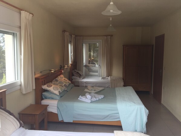 Un dormitorio con una cama grande, una mesita de noche, un armario y una ventana con cortinas.