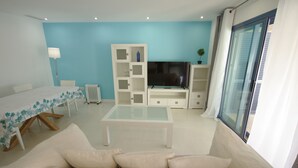 A modern living room with a sofa, a coffee table, a TV, and a white cabinet. - 40 - Apartamento Sugar (Tarifa)