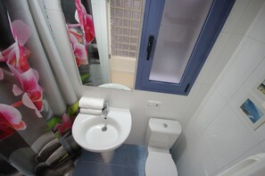 Une salle de bain comprenant un lavabo, des toilettes et un espace douche.