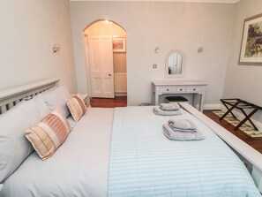 A neatly arranged bedroom with a bed, bedside tables, a dresser, and a mirror. - Glenander (Bamburgh)