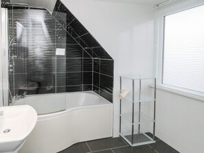 A modern bathroom with a freestanding bathtub, a glass shower enclosure, and a glass shelf unit. - Glenander (Bamburgh)