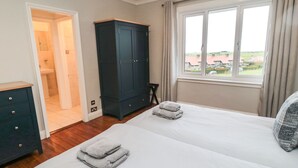 Un dormitorio con dos camas, un armario y una ventana con vistas a casas.