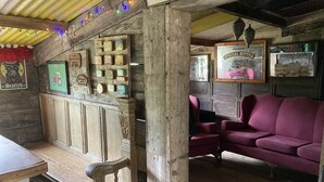 A rustic interior with wooden walls, a wooden bench, a red sofa, and various framed pictures and signs.