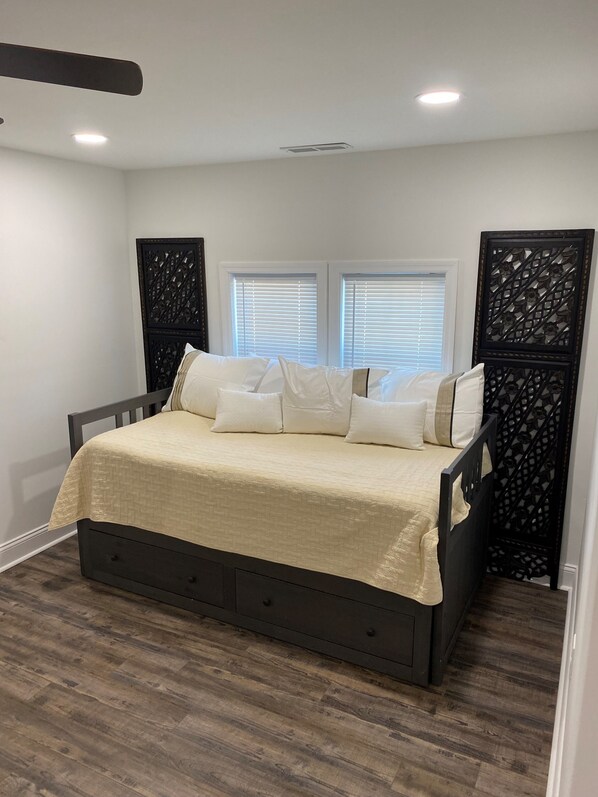 A bedroom with a bed, two windows, and a decorative partition.