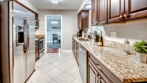 A modern kitchen with stainless steel appliances, granite countertops, and wooden cabinets. - Pool - Hot Tub - BBQ - Private Backyard (Cape Coral)
