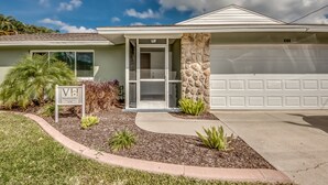 A single-story house with a stone exterior, a garage, and a well-maintained front yard with various plants. - Pool - Hot Tub - BBQ - Private Backyard (Cape Coral)